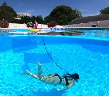 Person using the Nemo dive system for underwater breathing in a swimming pool, with the system's float visible on the surface