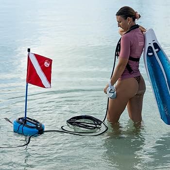 Person standing in shallow water with the BLU3 Nomad Dive System and a diver-down flag, preparing for a shallow water dive.