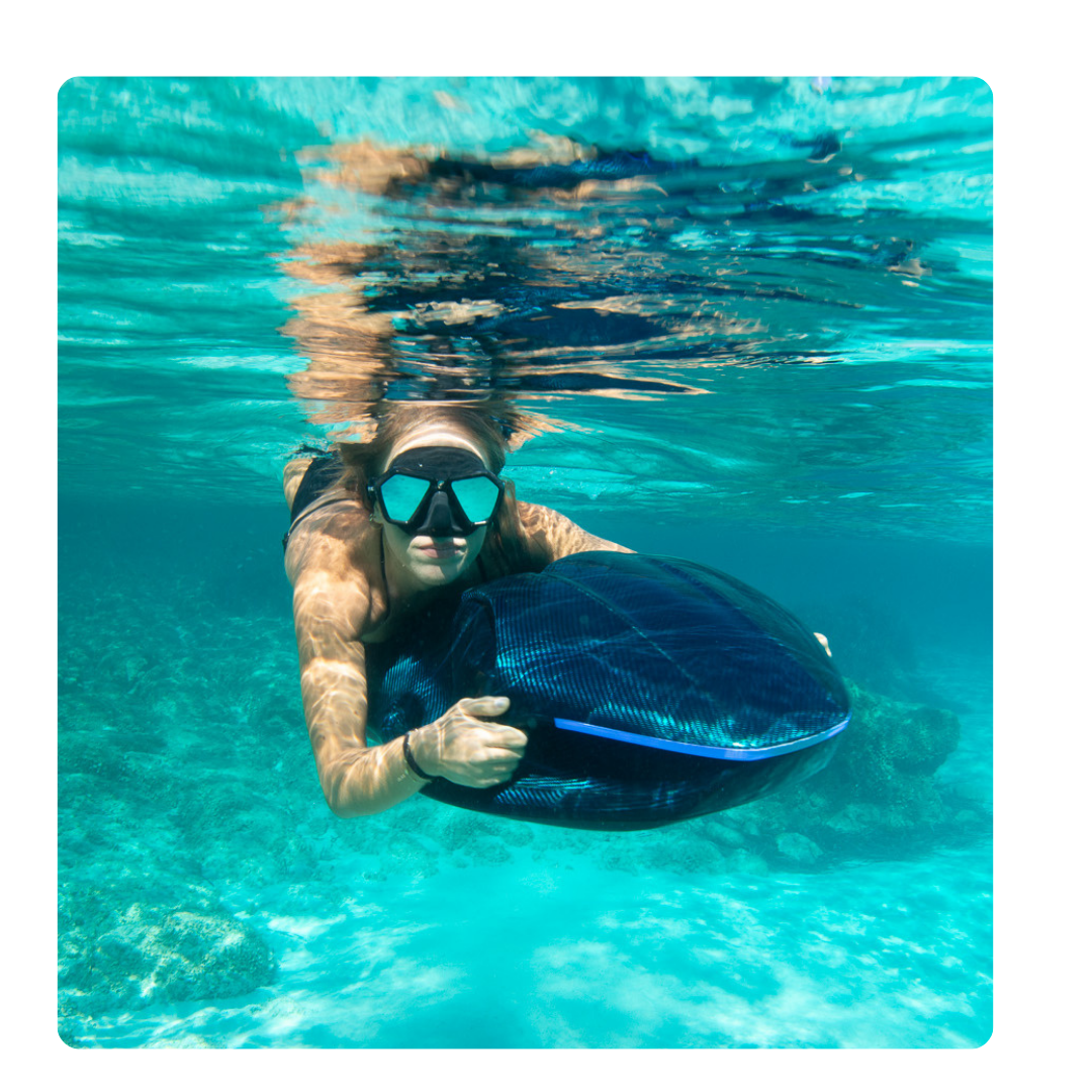 Diver demonstrating the SeaNXT Elite high-end underwater scooter in crystal-clear water