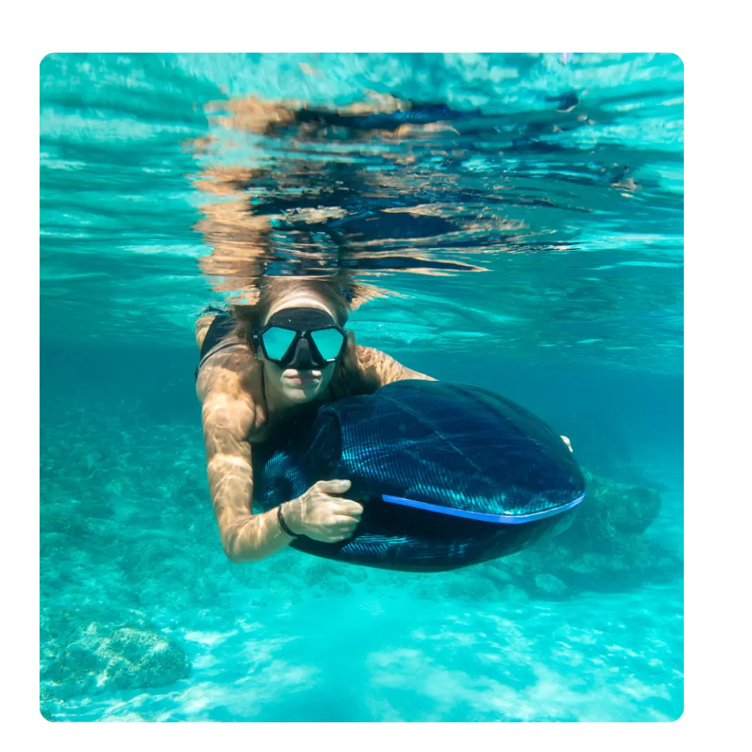 Diver demonstrating the SeaNXT Elite high-end underwater scooter in crystal-clear water